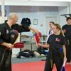 an instructor assisting a black belt to adjust a target